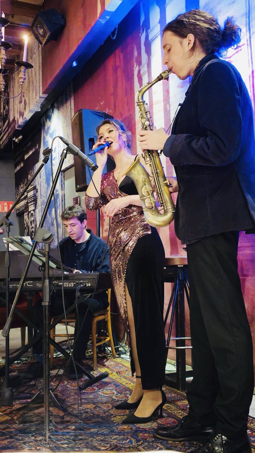 Ivett Karasz cantando con saxofonista y pianista
