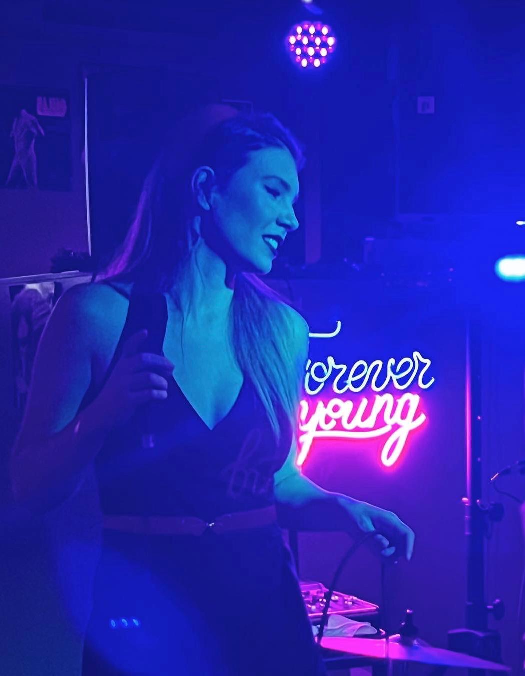 Ivett Karasz en escenario con luces de neón